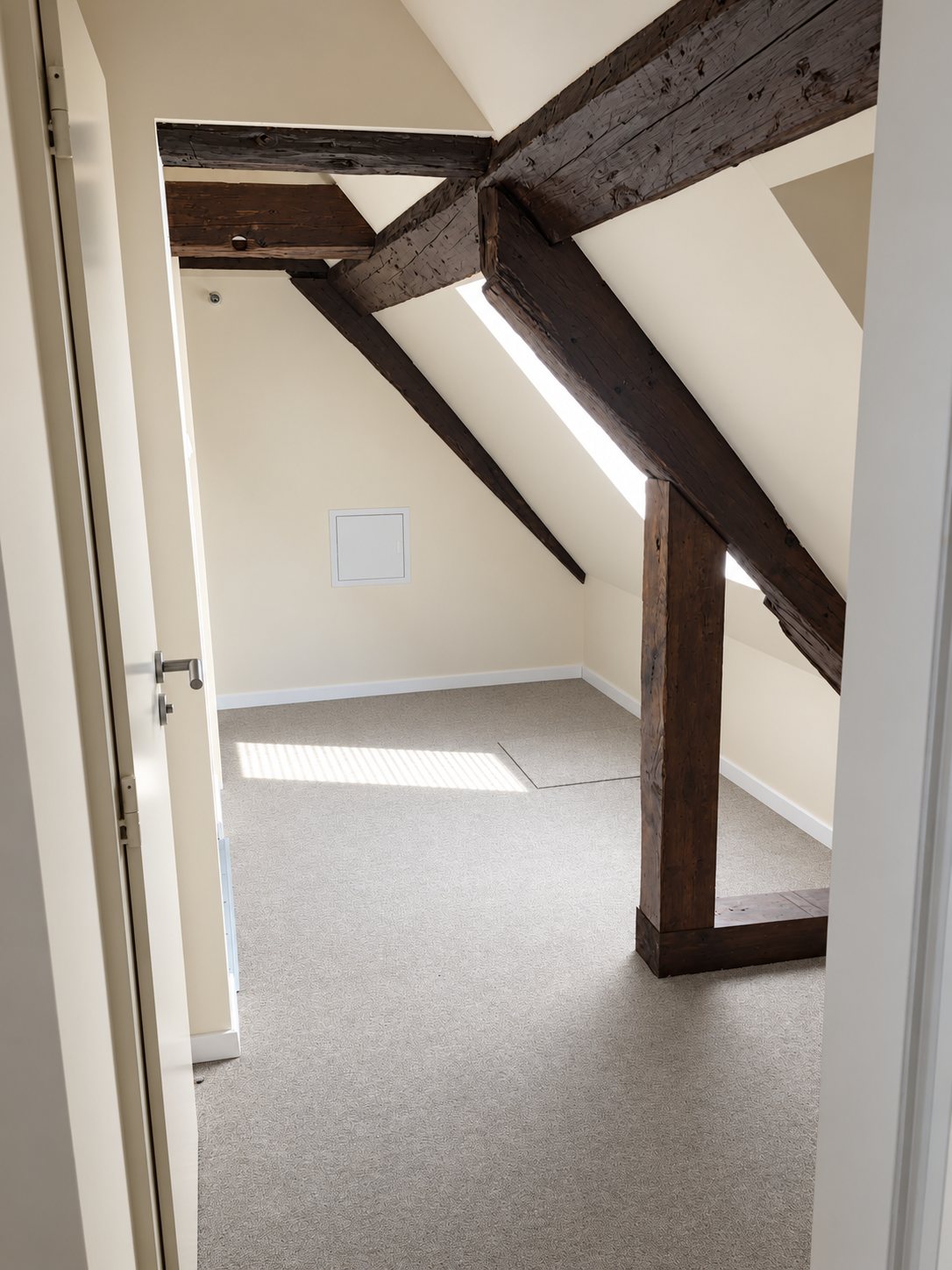 Réalisation KPAG, chambre mansardée rénovée avec poutres apparentes en bois foncé et moquette grise